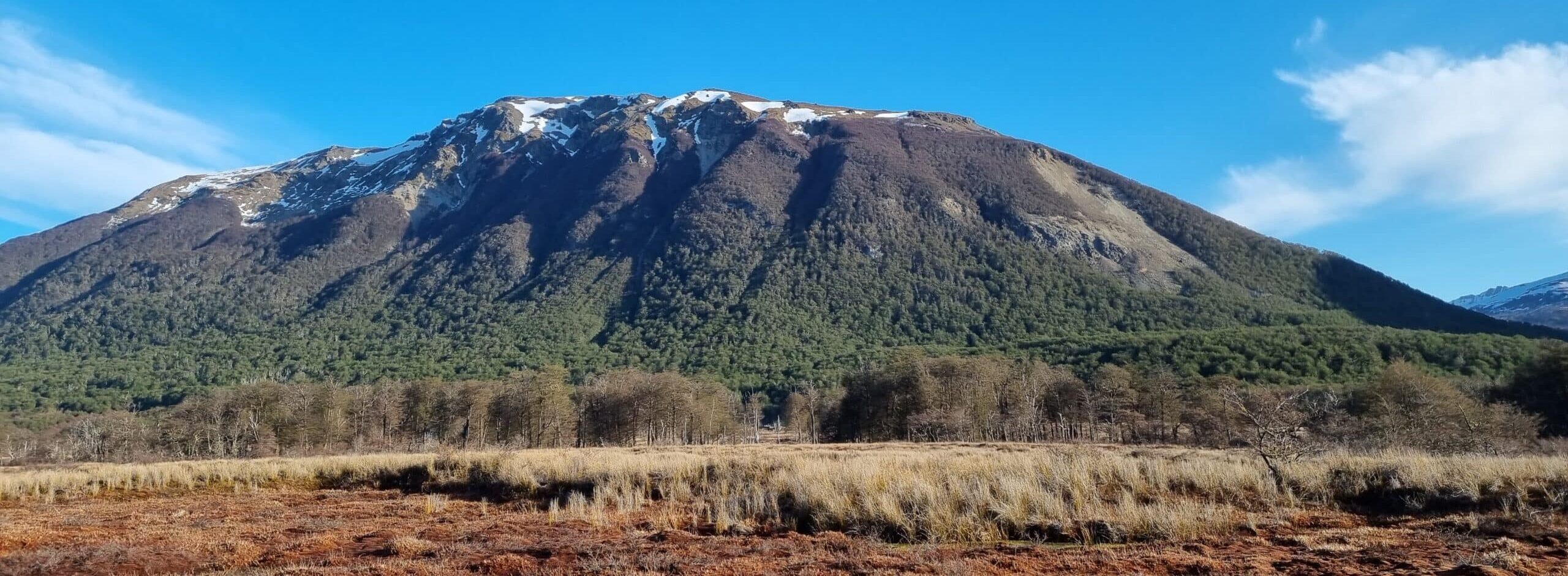 Imagen de una montaña junto a un turbal con un cielo celeste