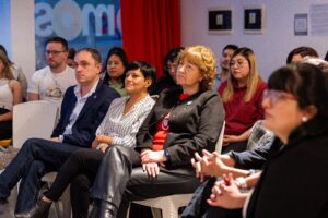 personas sentadas en el público escuchan atentamente