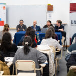 toma desde atrás en un aula de universidad, cuatro personas dando una conferencia