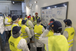 personas visitando una fábrica con chalecos de seguridad